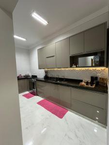 a large kitchen with gray cabinets and pink rugs at Laranjeiras House in Uberaba