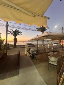 a patio with tables and umbrellas on the beach at Casa Almar in Algarrobo