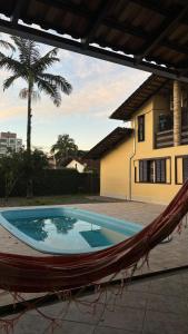 a hammock in front of a house with a pool at Econômica Joinville Hostel e Pousada in Joinville