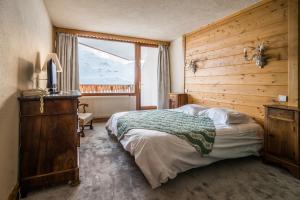 a bedroom with a bed and a large window at Hotel Le Portillo in Val Thorens