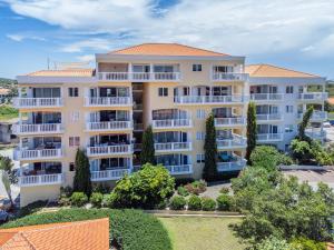 an apartment building with white balconies and trees at Blue Bay Apartments in Dorp Sint Michiel