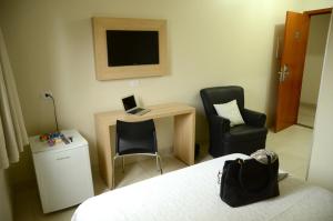 a bedroom with a desk with a laptop and two chairs at Hotel Capital in Cuiabá