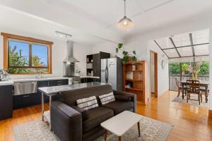a living room with a couch and a kitchen at Cabbage Tree Cottage in Papamoa