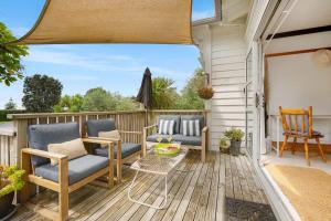 a patio with chairs and a table on a deck at Cabbage Tree Cottage in Papamoa