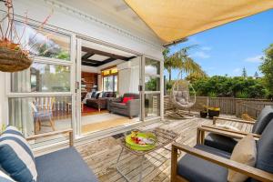 a screened in porch with a living room at Cabbage Tree Cottage in Papamoa +8 photos