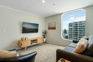 a living room with a couch and a window at Executive Oceanside Apartment in Mount Maunganui +15 photos
