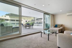 a living room with a couch and a glass table at Oceanside Apartment with Pool Views in Mount Maunganui