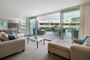 a living room with a couch and a table at Oceanside Apartment with Pool Views in Mount Maunganui
