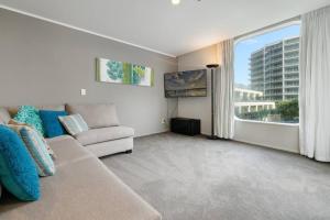 a living room with a couch and a large window at Oceanside Apartment with Pool Views in Mount Maunganui