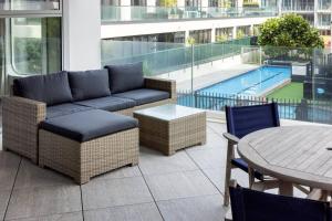 a patio with a couch and a table and a pool at Oceanside Apartment with Pool Views in Mount Maunganui