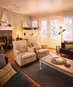 a living room with a couch and chairs and a fireplace at Auberge Beausejour in Les Éboulements