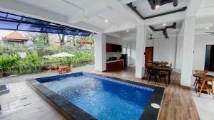 an indoor swimming pool in a living room with a table and chairs at Escotel Majestica in Dalung
