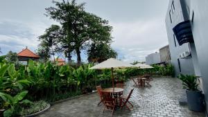 a patio with tables and chairs and an umbrella at Escotel Majestica in Dalung