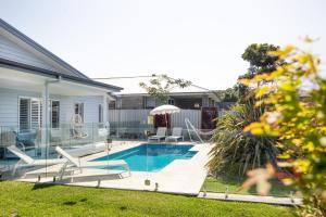 a swimming pool with chairs and an umbrella next to a house at Casa Azul in Burrill Lake
