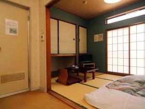 a room with a bed and a desk and a window at Hotel Sankyu in Tsukuba