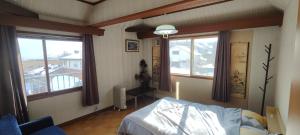 a bedroom with a bed and two windows at Nomad Gala Otaru in Otaru