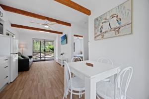 a dining room and living room with a white table and chairs at Agnes Bush Cabins in Agnes Water