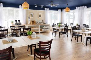 a dining room with white tables and chairs at Auberge Beausejour in Les Éboulements