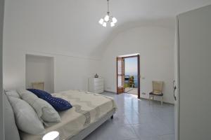 a white bedroom with a bed and a mirror at Casa Lisuccia in Furore