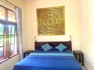 a bedroom with a blue bed with a painting on the wall at Villa Jaya in Lovina