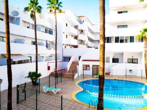 an apartment with a swimming pool and palm trees at Modern Studio with Pool & Terrace Playa de las Américas, Tenerife in Playa de las Americas