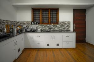a kitchen with white cabinets and a wooden floor at Cloud 9 Homestay, Thekkady in Thekkady