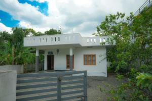 a white house with a fence in front of it at Cloud 9 Homestay, Thekkady in Thekkady