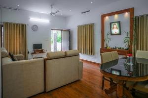 a living room with two couches and a glass table at Cloud 9 Homestay, Thekkady in Thekkady