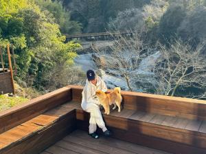 a man sitting on a wooden platform with a dog at and RIVER KATSUURA in Katsuura