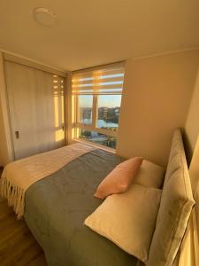 a bedroom with a bed and a large window at Acogedor departamento in Concepción