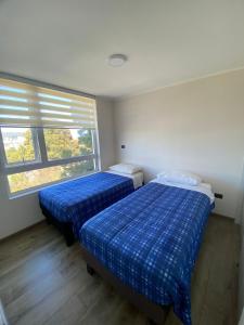 two beds in a room with a window at Acogedor departamento in Concepción +2 photos