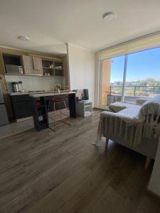 a room with a bed and a kitchen with a desk at Acogedor departamento in Concepción