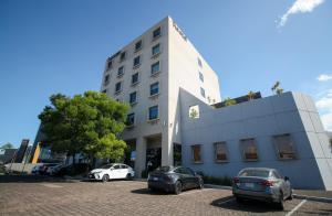 a white building with cars parked in a parking lot at Hotel Turotel Morelia in Morelia