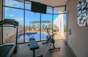 a fitness room with a gym with a swimming pool at Hotel Turotel Morelia in Morelia