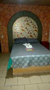 a bed in a room with a stone wall at LA HUERTA Cabaña y Hospedaje in Huasca de Ocampo