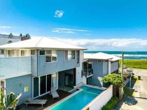 a house with a swimming pool in front of the ocean at The Beach House in Lennox Head