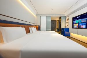 a hotel room with two beds and a flat screen tv at Mehood Hotel Xi'an Tumen Railway Station in Xi'an