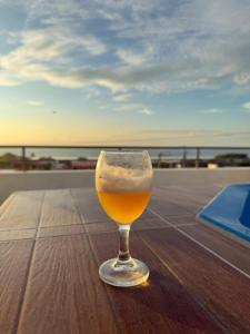 a glass of beer sitting on a table near the ocean at Casa Norte North Beach in Los Órganos