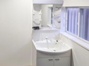 a white bathroom with a sink and a mirror at 旅館さくら in Takamatsu +31 photos