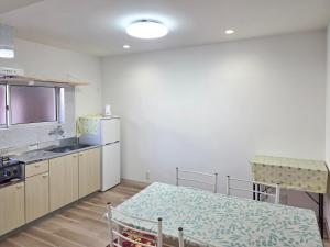 a small kitchen with a table and a refrigerator at 旅館さくら in Takamatsu