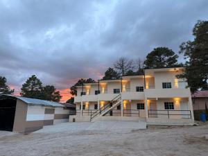 a large white building with a sunset in the background at HOTEL Y CABAÑAS El PINO in Creel