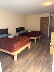 two beds in a room with wooden floors at HOTEL Y CABAÑAS El PINO in Creel