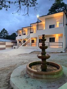 a building with a fountain in front of a building at HOTEL Y CABAÑAS El PINO in Creel +4 photos