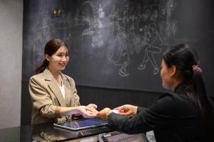 two women shaking hands at a table with a laptop at The Royal Park Canvas Nagoya in Nagoya