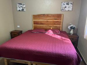 a bed with a purple bedspread and two pillows at Cabaña el Pino 1 in Creel