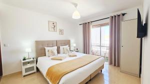 a white bedroom with a bed and a balcony at Baleal Beach Stay in Baleal
