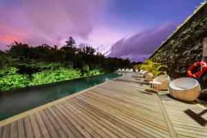 a wooden deck with chairs and a body of water at Villa Vatama Jimbaran in Jimbaran