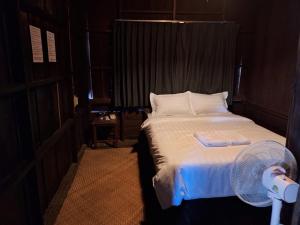 a bedroom with a white bed with a fan at Vang Vieng Ban Lao Guesthouse in Vang Vieng