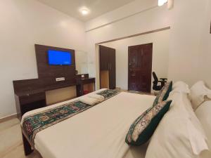 a bedroom with two beds with a tv on the wall at Sarovar Morjim in Morjim +44 photos