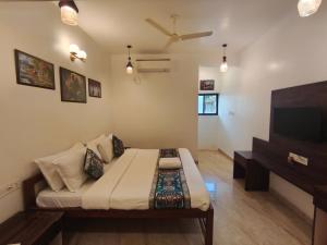 a living room with a bed and a flat screen tv at Sarovar Morjim in Morjim